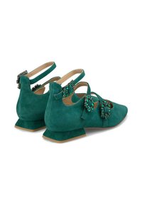 Zapatos de ante verde con un tacón bajo y cuadrado. Presentan acentos decorativos de joyas y correas ajustables para un ajuste seguro.