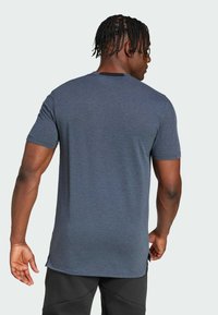 Camiseta de manga corta y cuello redondo en azul marina jaspeado, con dobladillo recto y un sutil logotipo en la parte inferior. Tejido suave y ligero.