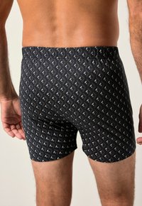 Boxer da uomo neri con motivo e vita elastica. Presenta un design geometrico in bianco e marrone chiaro, realizzati in tessuto morbido.