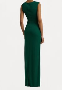 Grön, ärmlös maxi-klänning med figurnära liv och utsvängd kjol, utrustad med dragkedja i ryggen och sidoflik för ökad rörelsefrihet.