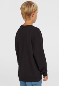 Sudadera negra de tejido suave, con cuello redondo, mangas largas y corte relajado. Presenta puños y bajo de canalé para mayor comodidad.
