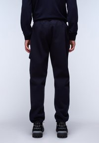 Navy sweatpants in soft fabric, featuring a relaxed fit, elastic waistband, side pockets, and ribbed cuffs. Finished with minimal stitching details.