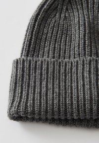 Beanie in lana lavorata a maglia di un grigio scuro con risvolto, caratterizzato da un motivo a coste verticali su uno sfondo bianco.