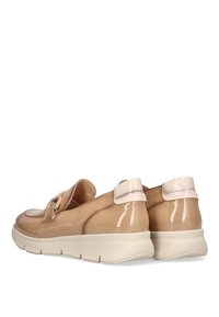 Zapatillas beige brillantes con puntera redonda y banda de velcro, que presentan una suela blanca gruesa y un diseño elegante, vistas desde la parte posterior.