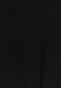 Tissu noir côtelé avec une texture lisse, présentant une fente latérale. Le matériau semble extensible et doux.