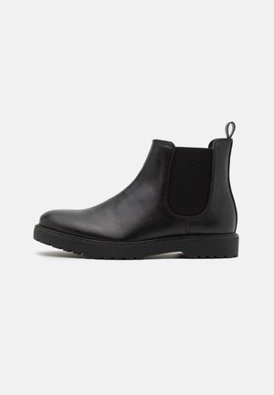 Bottines Chelsea en cuir noir avec des panneaux élastiques sur les côtés, un embout arrondi et une semelle en caoutchouc texturé pour une meilleure adhérence et durabilité.