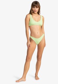 Lys grøn ribbet bikinidrakt med croppet topp og høy midje-bunn. Glatt tekstur og minimalistisk design med brede skulderstropper.