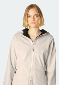 Světlá šedá nepromokavá bunda vyrobená z hladkého materiálu. Má černou podšívku kapuce, přední zip a dvě postranní kapsy na zip.