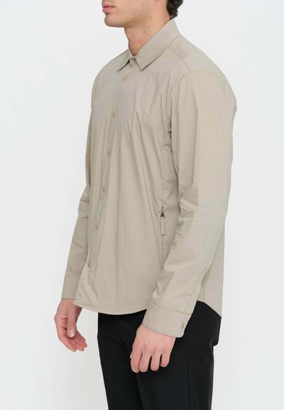 Camicia button-up beige chiaro con maniche lunghe, dotata di colletto, bottoni a scatto e orlo regolabile, realizzata in tessuto liscio.