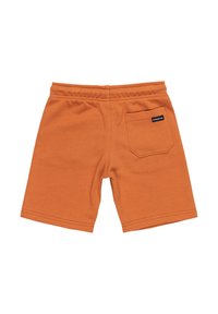 Berlins de algodón naranja con una textura suave, cinturilla elástica y un bolsillo trasero que presenta una pequeña etiqueta de la marca. Costuras planas terminan los bordes.