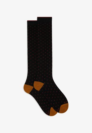 Calze nere al ginocchio con pois rossi, aree del dito e del tallone in contrasto marrone, texture liscia e dettaglio a coste sulla parte superiore.