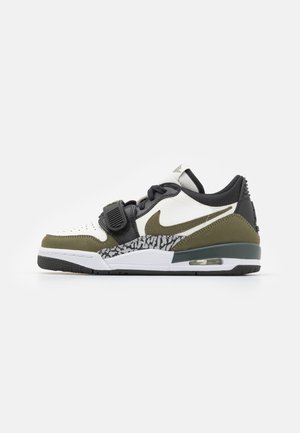 Sapatilhas Nike com uma combinação de cores em preto, verde oliva e branco, detalhes em couro texturizado e um padrão distinto de impressão de elefante.