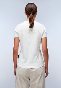 Witte katoenen T-shirt met korte mouwen, voorzien van een grafisch ontwerp op de achterkant in lichtbeige, gecombineerd met lichtbeige cargo-broek.