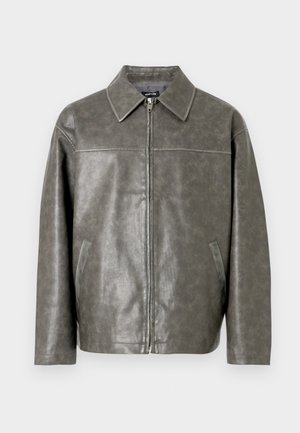 Szürke műbőr dzseki cipzáras rögzítéssel, hegyes gallérral, oldalzsebekkel és sima textúrával. Minimalista dizájnt és testre szabott szabást kínál.