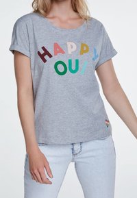 T-shirt en coton gris à manches courtes, avec un texte coloré "HAPPY OUI" et un petit graphique en forme de cœur arc-en-ciel en bas.