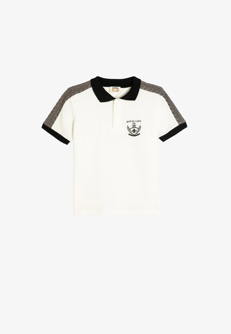 Hvid polo skjorte med sort krave og ærmer, der har en struktureret grå stof på skuldrene og et brystemblem med teksten "ROYAL LIFE."