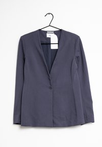 Marinblå kavaj tillverkad av mjukt tyg, med notchsinfällning, en enkel knappstängning och långa ärmar. Hänger från ett svart kroksystem.