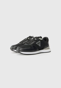 Black athletic sneakers with mesh panels and synthetic accents. Features a white sole and a triangular logo on the side. Lace-up design.
