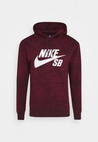 Bordeaux huppari, jossa on teksturoitu kuosi, valkoinen "NIKE SB" -logo rinnassa, nyörillä varustettu huppu ja etupuolella kenguru-tasku.