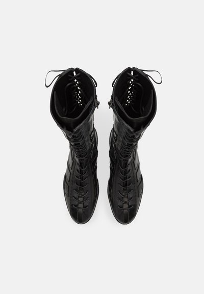 Bottines noires à lacets avec un bout étroit, en cuir texturé, et un design découpé en haut. Présentent une tige haute et des accents cousus.