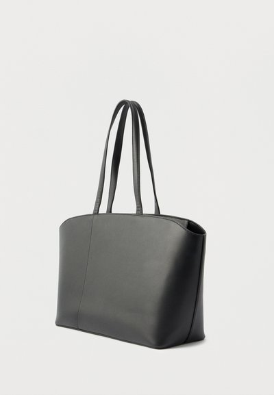 Sac à main en cuir noir avec deux longues anses d'épaule, forme rectangulaire structurée et surface lisse sur un fond clair uni.