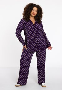 Paarse pyjama set met een geometrisch patroon in crème en goud. Lange mouwen, knopenblouse en broek met wijde pijpen van een zachte stof.