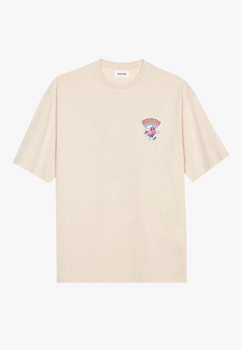 T-shirt en coton couleur crème avec une coupe ample, comportant un petit graphique brodé d'un personnage et le mot "BRAIN" en rouge et bleu.