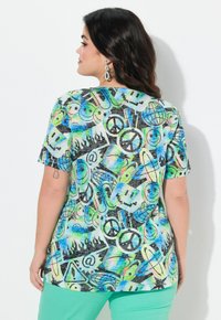 Camisa de manga corta con un diseño de patrones multicolores de símbolos e íconos sobre un fondo oscuro. Mezcla de algodón, corte relajado.