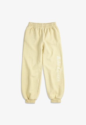 Pantaloni jogger in pile beige chiaro con fascia elastica in vita e polsini, con la scritta "Bobo Choses" stampata verticalmente sulla gamba destra.