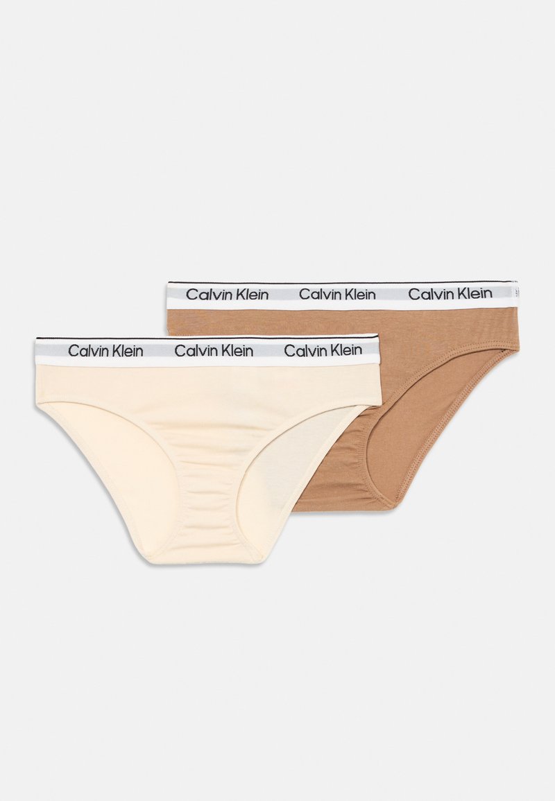 Két pár tejszínből és világosbarnából készült pamutzokni, fekete gumis derékkal, amelyen a "Calvin Klein" logó található. Sima textúra, klasszikus dizájn.
