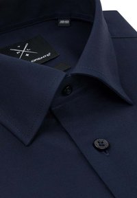 Granatowa koszula z wyraźnym kołnierzykiem, zapięciem na guziki z przodu oraz teksturowanym materiałem. Zawiera metkę z informacjami o rozmiarze.