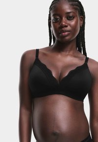 Soutien-gorge noir orné de dentelle avec un design en V et des bretelles réglables, doté d'un tissu lisse et d'une texture douce et extensible.