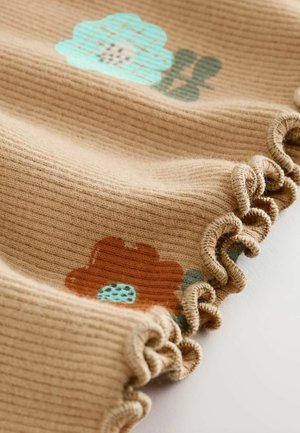 Tessuto beige a coste con motivi floreali, caratterizzato da un fiore blu e un fiore marrone. I bordi presentano un dettaglio di volant arricciato.