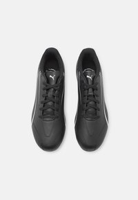 Scarpe sportive nere con tomaia sintetica liscia, punta arrotondata, accenti laterali bianchi e lacci neri. Design minimalista, suola piatta.