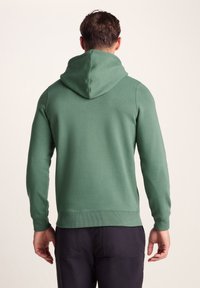 Green hooded sweatshirt made of soft cotton blend. Features ribbed cuffs and hem, kangaroo pocket, and a relaxed fit. Simple design, no patterns.
