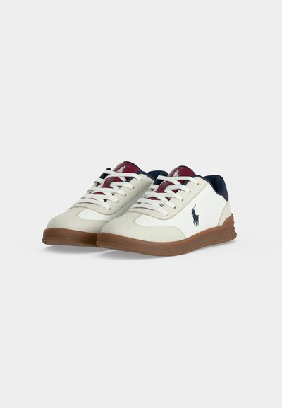 Ζευγάρι λευκά και μπεζ sneakers χαμηλού προφίλ με καφετιά σόλα, λευκά κορδόνια, ναυτικό τακούνι και σκοτεινό λογότυπο στη πλευρά και στη γλώσσα.