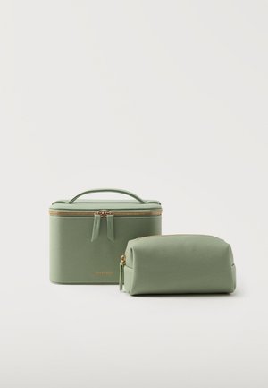Deux trousses de maquillage vert clair avec des fermetures éclair dorées, une rectangulaire avec une poignée et une pochette arrondie, sur un fond blanc uni.