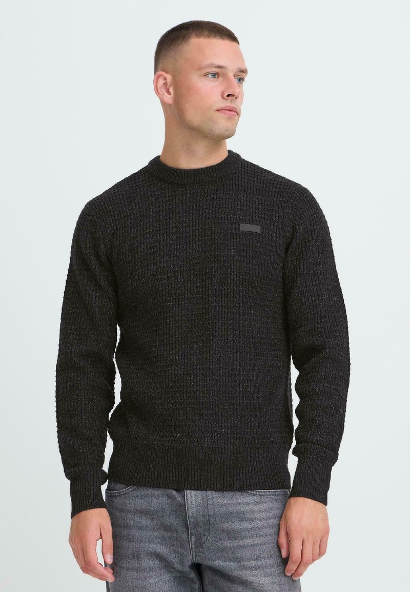 Sort strikket sweater med et tekstureret mønster, rund halsudskæring og båndede ærmer. Har et lille, minimalistisk logo på brystet.