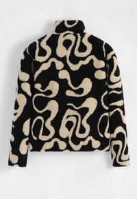 Veste floue noire et beige avec un col montant, présentant un motif de tourbillon abstrait et un tissu texturé et confortable.