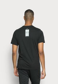 Sort bomulds t-shirt med et grafisk design på ryggen med teksten "SOLE FOOD." Rund halsudskæring og korte ærmer, standard pasform.