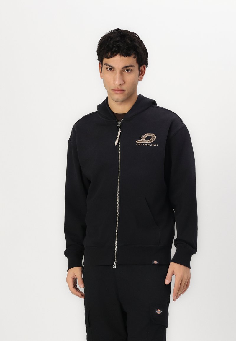 Črna zip-up kapuca z sprednjim žepom in logotipom na levi strani prsnega dela. Ima kapuco z vrvico in rebraste manšete. Mehka tekstura tkanine.