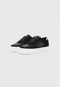 Sneaker nere con un mix di materiali in pelle e camoscio, dotate di una suola bianca, punta perforata e lacci tono su tono.