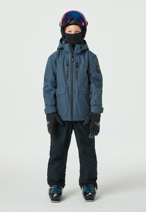 Kinder-Skianzug bestehend aus einer dunkelblauen wasserdichten Jacke mit mehreren Taschen, schwarzen Schneehosen, schwarzen Handschuhen und Skibrille mit verspiegelt Gläsern.