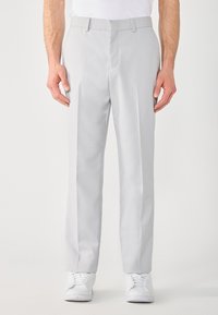 Graue maßgeschneiderte Hose mit glatter Textur, flacher Vorderseite und schmalem Schnitt, kombiniert mit weißen Sportschuhen.