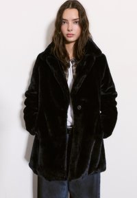 Czarny płaszcz z sztucznego futra z kołnierzem z klapami, z zapięciem na guziki, długimi rękawami i kieszeniami po bokach, charakteryzujący się miękką, teksturowaną powierzchnią.