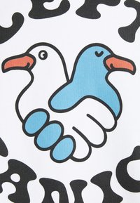 Illustrazione di due uccelli cartoni: uno bianco con un becco arancione e l'altro blu, tenuti in una mano stilizzata bianca su uno sfondo bianco.