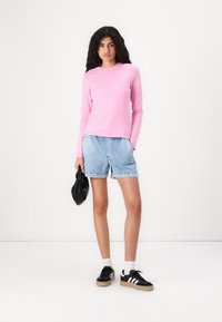 Roosa pikakäised tipp, helesinised denim lühikesed püksid, must kott ja mustad tossud valgete triipudega. Lihtne disain, juhuslik sobivus ja pehmed tekstuurid.