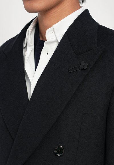 Cappotto di lana blu navy con finitura testurizzata, caratterizzato da reversed lapels, un bottone nero rotondo e un fermaglio floreale sul colletto.