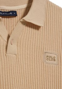 Béžová žebrovaná polo košile vyrobená z měkkého materiálu, s tříknoflíkovým zapínáním a obdélníkovým logem "POLO CLUB" na hrudi.