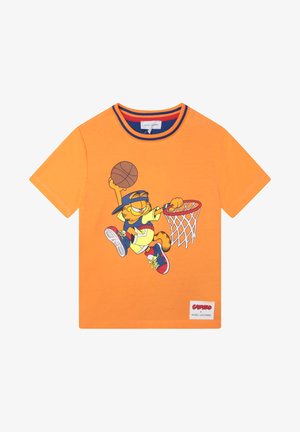 T-shirt en coton orange avec un personnage de dessin animé en position de basketball, doté d'un design graphique et d'un col contrastant bleu et rouge.